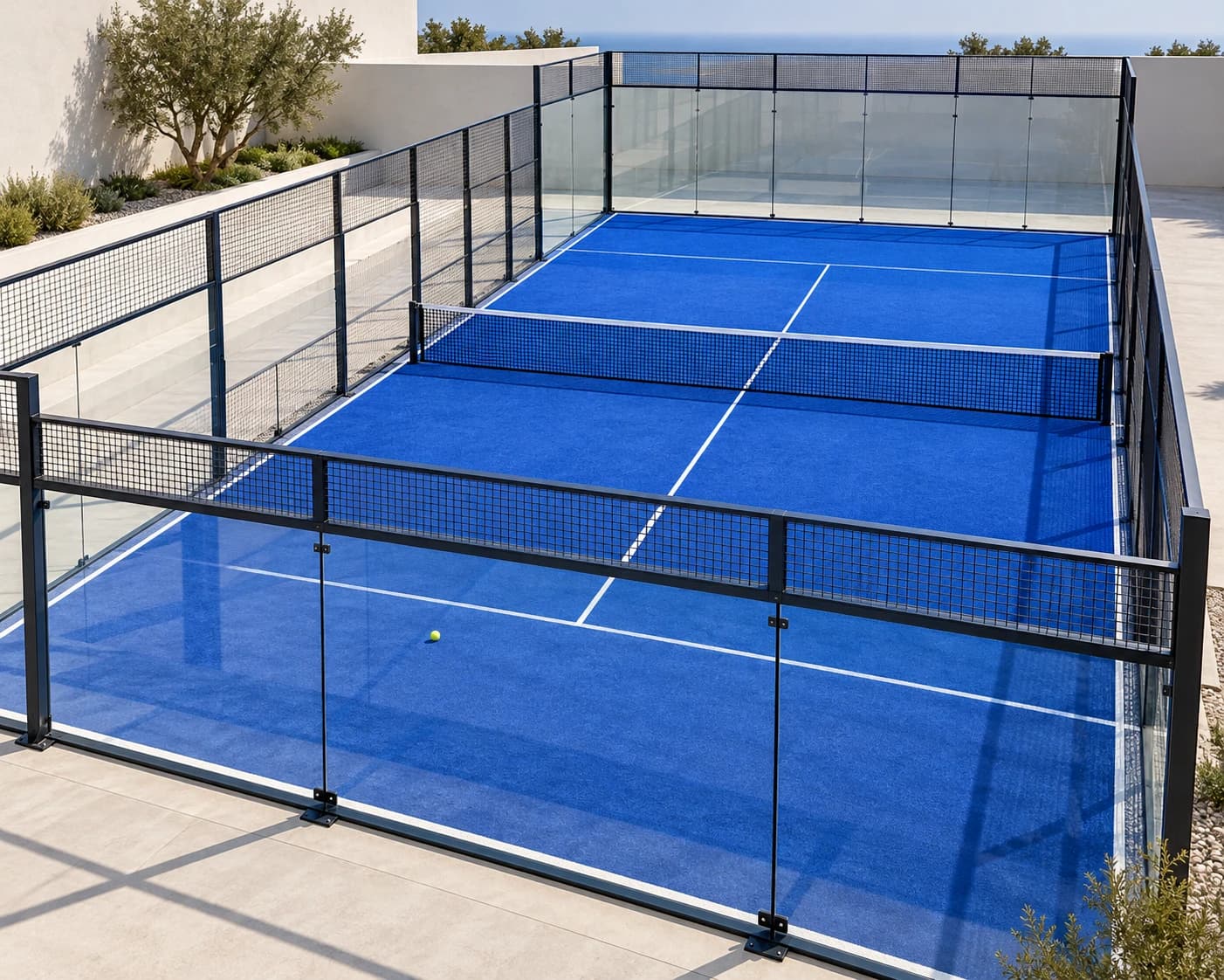 Sunlit blue padel court with glass walls and a central net